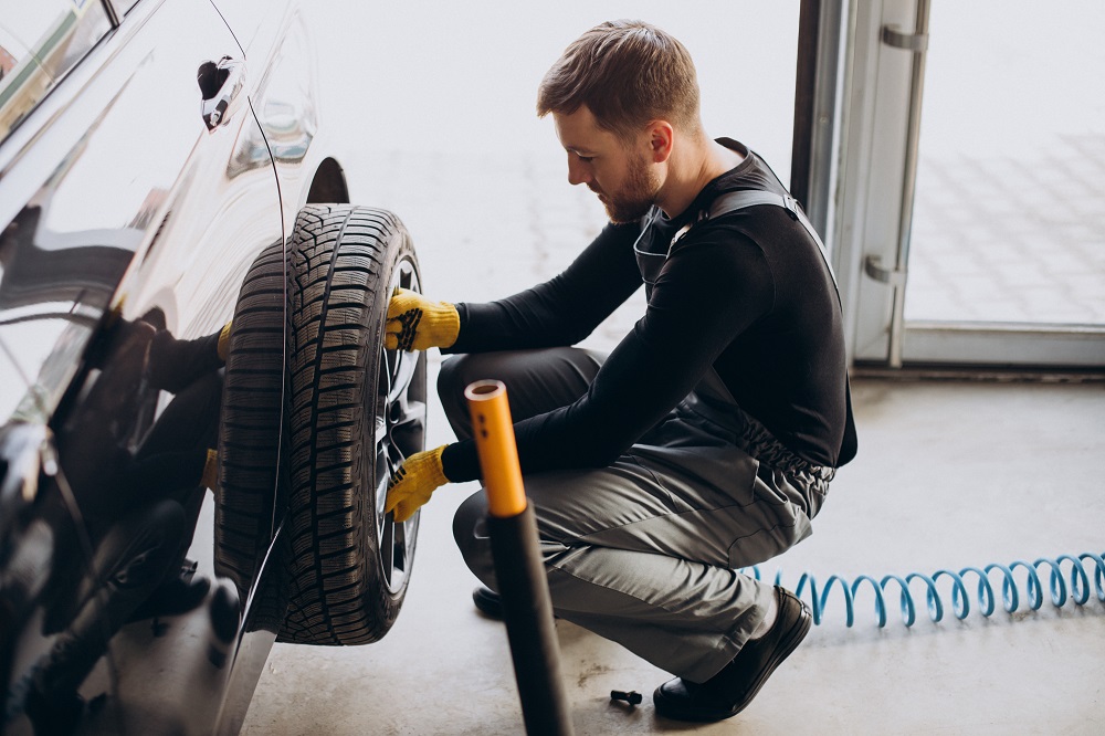 Car mechanic changing wheels in car